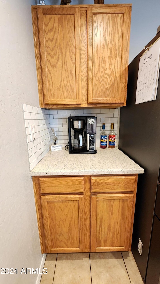 kitchen featuring light tile patterned flooring, decorative backsplash, and light stone counters