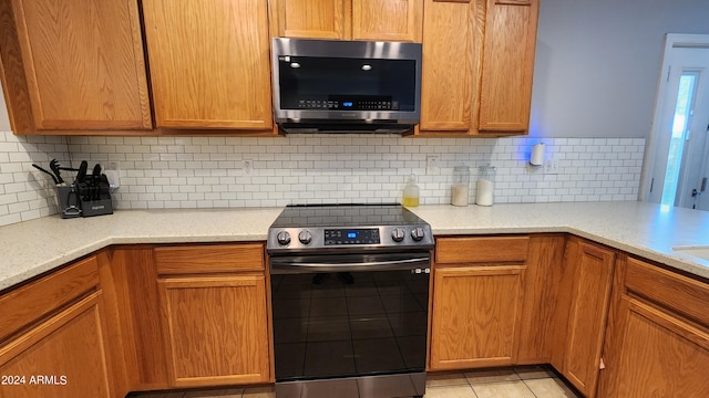 6349 W Valencia Dr, Laveen, AZ 85339 - kitchen featuring light stone countertops, backsplash, appliances with stainless steel finishes, and light tile patterned flooring