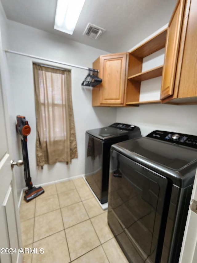 washroom with light tile patterned floors, cabinets, and washer and clothes dryer