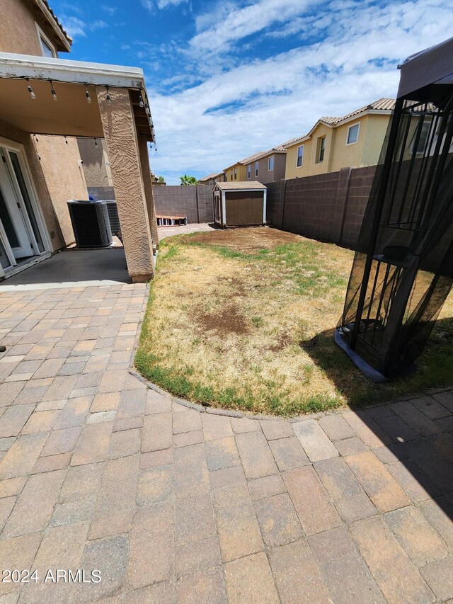 view of yard featuring central air condition unit, a patio area, and a storage shed