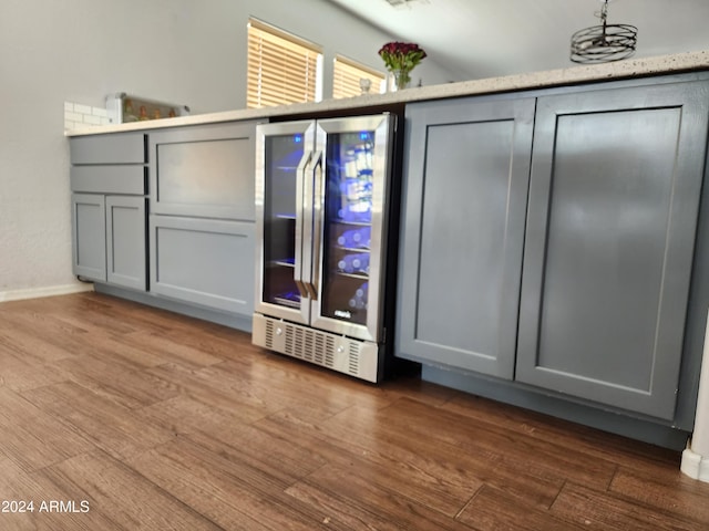 interior space with wood-type flooring, beverage cooler, and gray cabinets