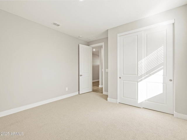 unfurnished bedroom featuring light colored carpet and a closet