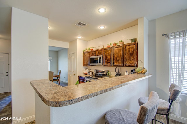 kitchen with baseboards, a peninsula, light countertops, visible vents, and stainless steel appliances