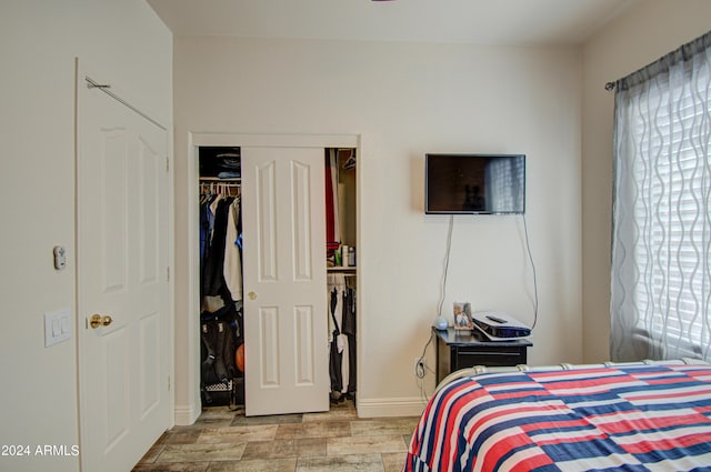 bedroom featuring light wood-type flooring, a closet, baseboards, and multiple windows
