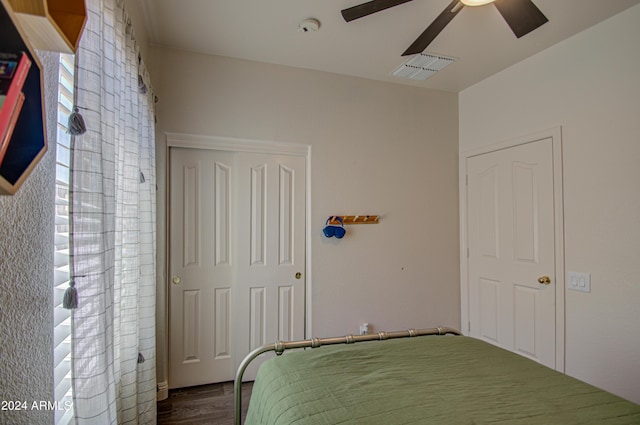 bedroom with dark wood-type flooring, a closet, a ceiling fan, and visible vents