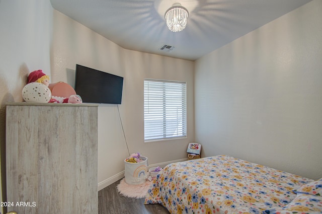 bedroom featuring a notable chandelier, visible vents, baseboards, and wood finished floors