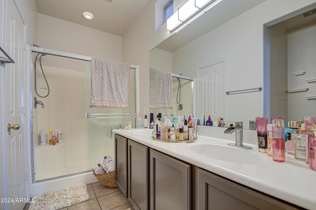 bathroom featuring double vanity, tile patterned flooring, a shower stall, visible vents, and a sink