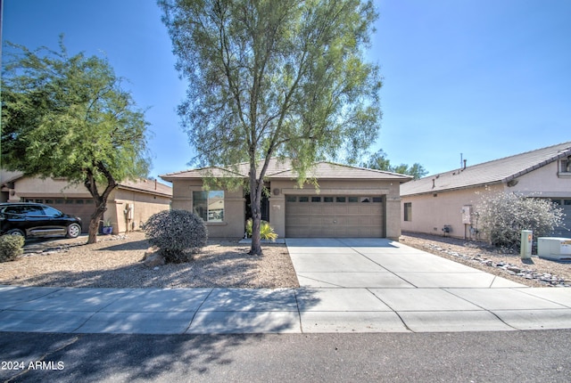 ranch-style house featuring driveway, a tiled roof, an attached garage, and stucco siding