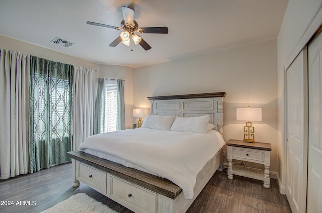 bedroom with a closet, a ceiling fan, visible vents, wood finished floors, and baseboards