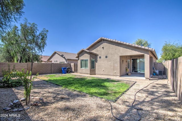 back of house with stucco siding, a patio area, a fenced backyard, central AC, and a lawn