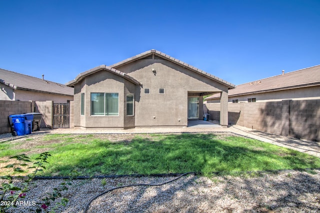 back of property with a patio area, a tiled roof, a yard, a fenced backyard, and stucco siding