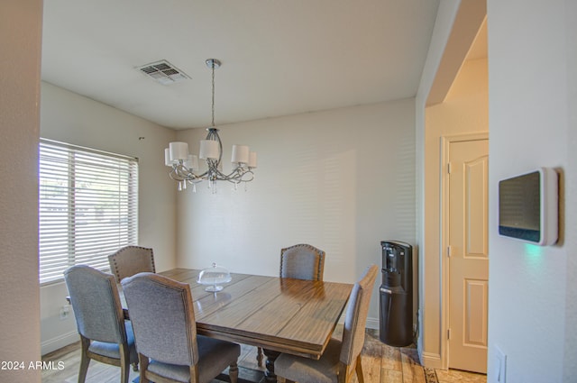 dining room featuring light wood finished floors, visible vents, baseboards, and an inviting chandelier