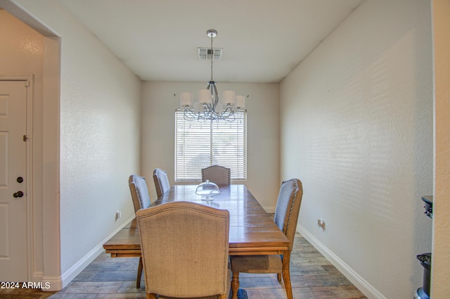 dining space featuring baseboards, wood finished floors, a notable chandelier, and visible vents