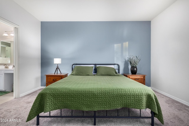 carpeted bedroom with ensuite bath and sink