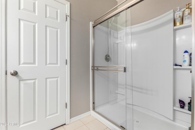 bathroom with a shower with door and tile patterned floors