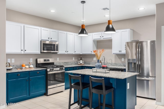 kitchen featuring a center island, white cabinetry, appliances with stainless steel finishes, decorative light fixtures, and blue cabinetry