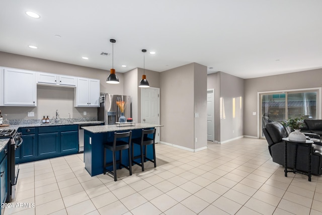 kitchen featuring light stone counters, a center island, hanging light fixtures, stainless steel appliances, and blue cabinets