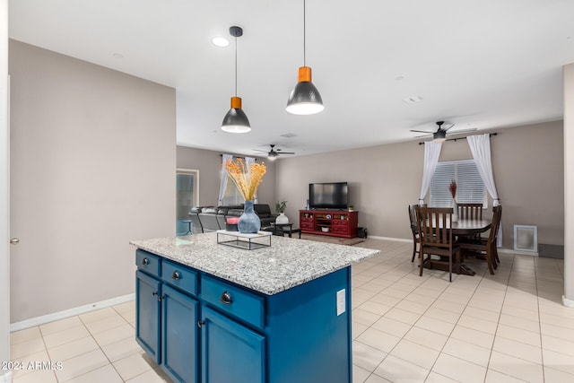 kitchen with pendant lighting, a kitchen island, light stone countertops, ceiling fan, and blue cabinetry