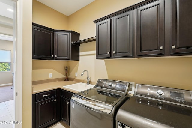 clothes washing area featuring washer and dryer, sink, light tile patterned floors, and cabinets