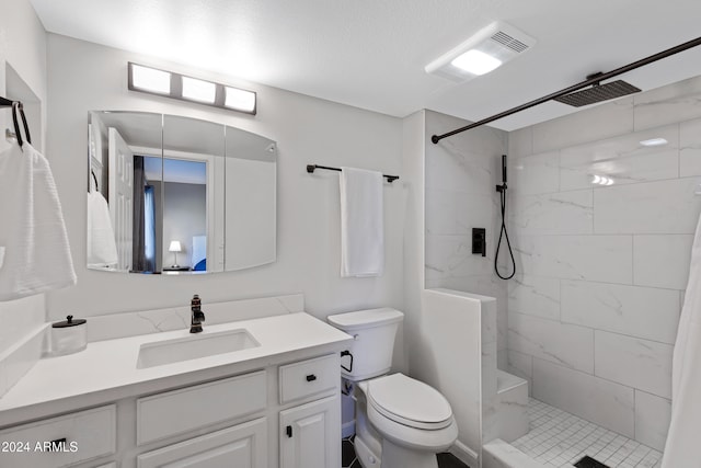 bathroom with a tile shower, vanity, and toilet