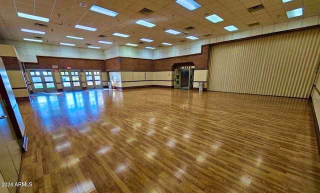 interior space with a high ceiling, a drop ceiling, and wood-type flooring