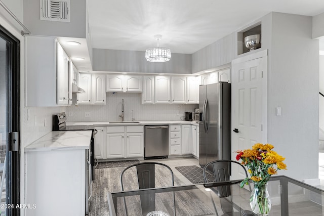 kitchen with appliances with stainless steel finishes, tasteful backsplash, light stone counters, sink, and white cabinets