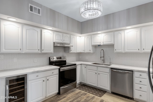 kitchen with appliances with stainless steel finishes, tasteful backsplash, beverage cooler, sink, and white cabinetry