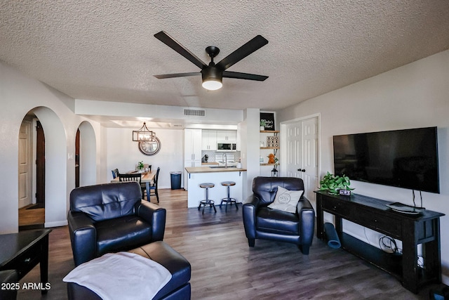 living room with sink, a textured ceiling, dark hardwood / wood-style floors, and ceiling fan