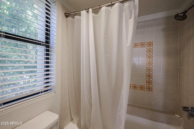 bathroom with shower / bath combo with shower curtain and a wealth of natural light