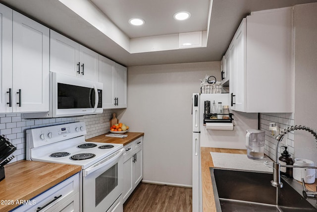 kitchen featuring sink, white appliances, white cabinets, and a tray ceiling