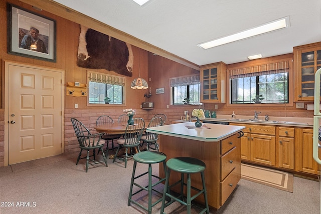 kitchen featuring a kitchen island, pendant lighting, a kitchen bar, sink, and light carpet