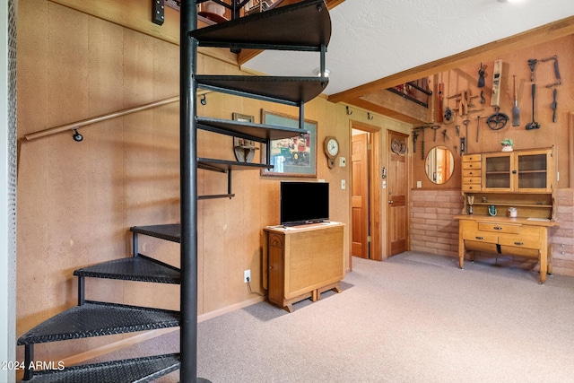 stairway featuring a textured ceiling, wood walls, and carpet