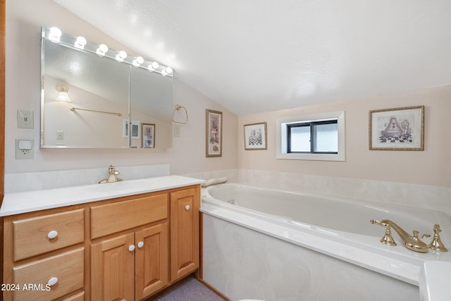 bathroom with lofted ceiling, vanity, and a bathtub