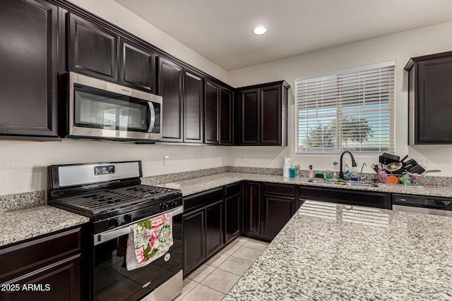 kitchen with light stone countertops, sink, light tile patterned flooring, and stainless steel appliances