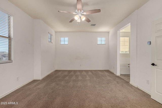 carpeted empty room featuring ceiling fan and a wealth of natural light