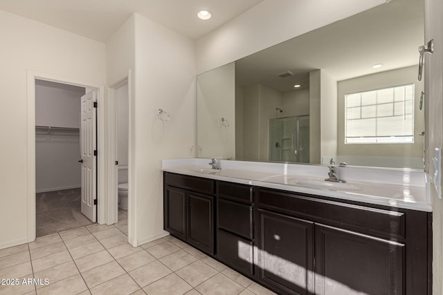 bathroom featuring tile patterned flooring, vanity, toilet, and a shower with shower door