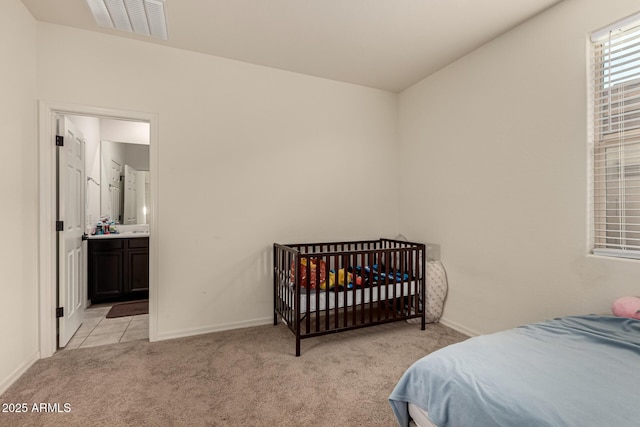 bedroom with light colored carpet and connected bathroom