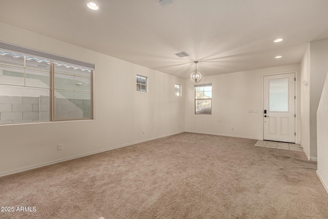 carpeted empty room with a notable chandelier