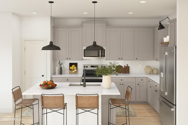 kitchen with light wood finished floors, backsplash, a kitchen bar, light countertops, and appliances with stainless steel finishes