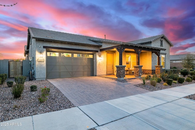 view of front of home featuring a gate, decorative driveway, a garage, and stucco siding