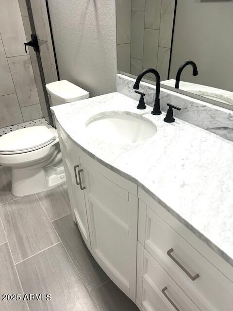 full bath featuring toilet, a stall shower, and vanity