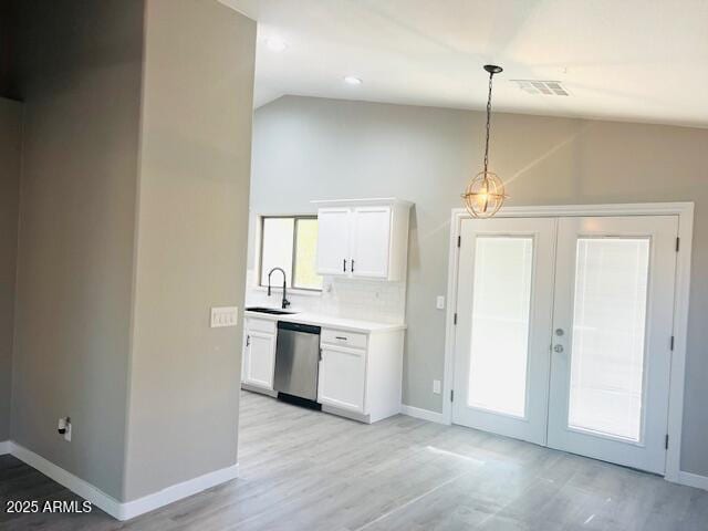 kitchen featuring white cabinetry, stainless steel dishwasher, a sink, light countertops, and vaulted ceiling