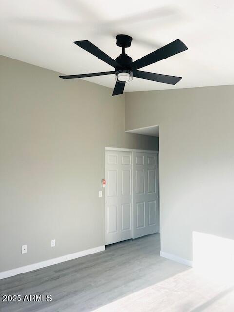 unfurnished room with a ceiling fan, light wood finished floors, and baseboards