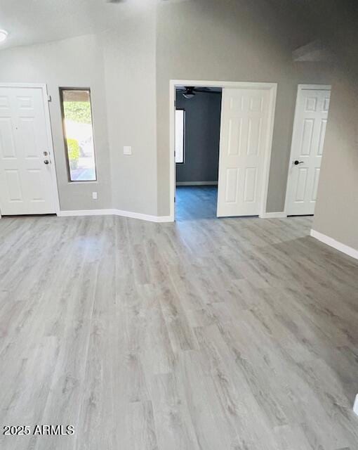 unfurnished living room with vaulted ceiling, wood finished floors, and baseboards