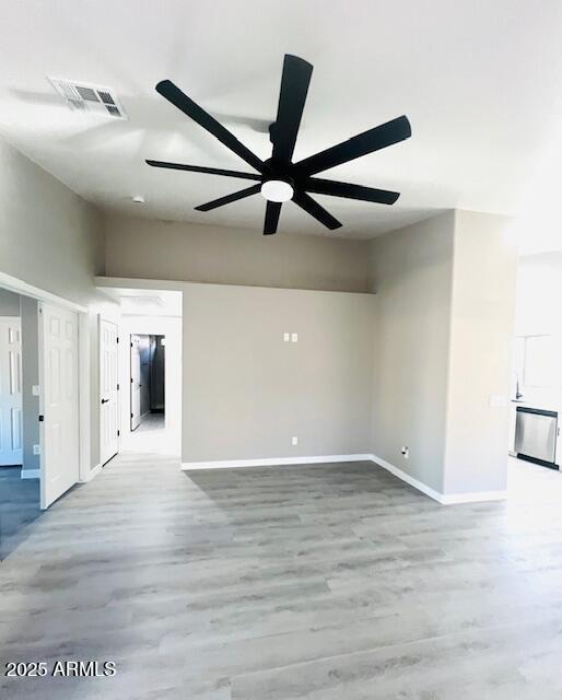 unfurnished living room with a ceiling fan, visible vents, wood finished floors, and baseboards