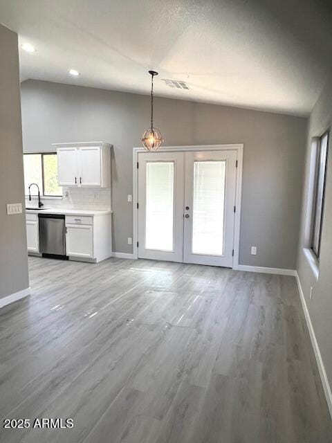unfurnished living room featuring light wood-type flooring, visible vents, baseboards, french doors, and lofted ceiling