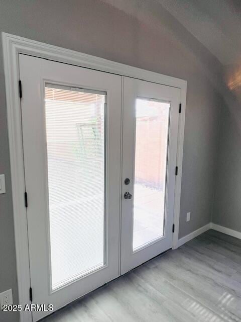 doorway with baseboards, light wood-style floors, and french doors