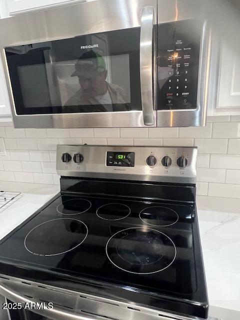 details with tasteful backsplash, stainless steel appliances, light countertops, and white cabinets