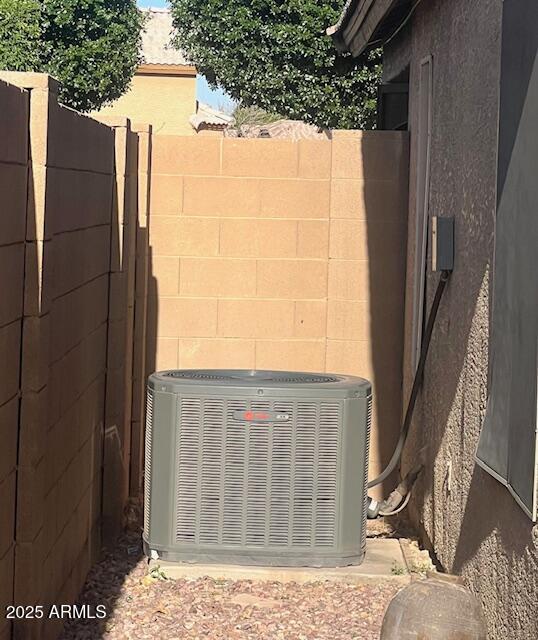 exterior details featuring fence, cooling unit, and stucco siding