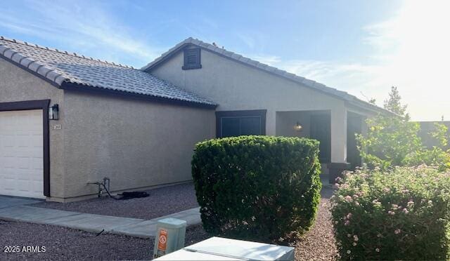 view of home's exterior featuring an attached garage, a tile roof, and stucco siding